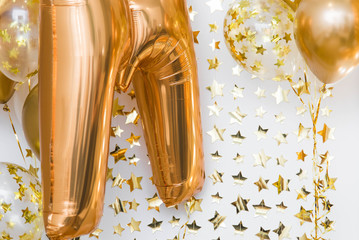 photozone of the birthday studio in the loft style, filled with sunlight gold balloons against awhite wall with paper stars background