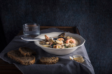 Clam chowder in a white plate. The main ingredients are shellfish, broth, butter, potatoes and onions.
