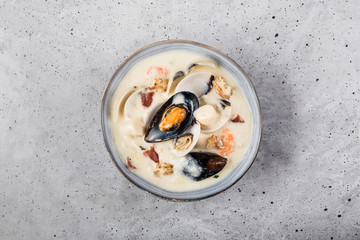 Clam chowder in a gray plate. The main ingredients are shellfish, broth, butter, potatoes and onions.