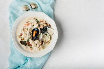 Clam chowder in a white plate. The main ingredients are shellfish, broth, butter, potatoes and onions. - obrazy, fototapety, plakaty