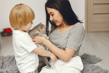 Beautiful woman with child. Woman in a gray t-shirt. Family playing with a cat.