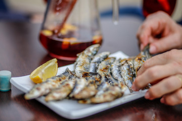Frische Sardinen mit Zitrone auf einem weißen Teller und Sangria im Hintergrund