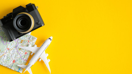 Travel planning concept. Flat lay traveler accessories on yellow background with copy space. Top view plane, map, vintage camera. Travel agency banner design template