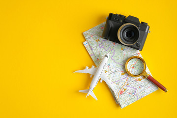 Travel accessories on yellow background. Vintage camera, airplane, magnifying glass and map....