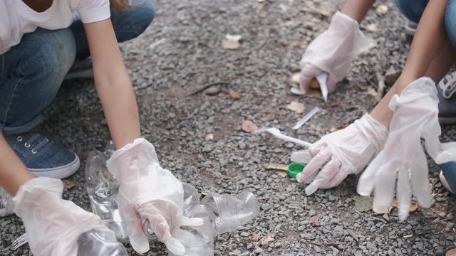 People collect the garbage. They wear the gloves. Children help to pick up the rubbish.