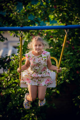 Adorable girl having fun on a swing on summer day