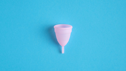 Reusable menstrual cup isolated on blue background. Alternative menstrual hygiene product. Critical...