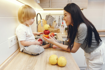 Cute little boy with mother. Family in a kitchen. Mother with son eating fruits.