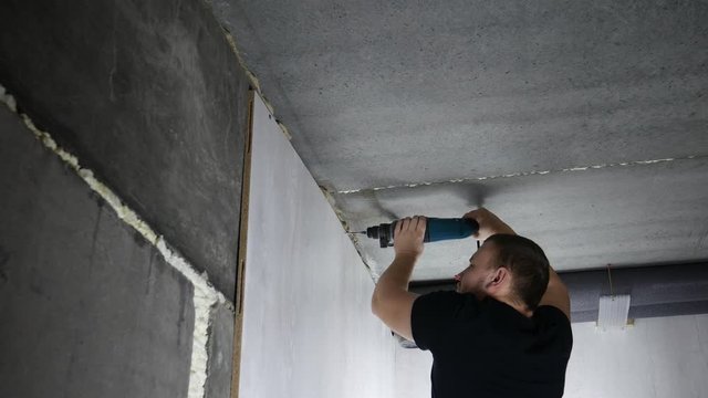 Builder makes a hole in a concrete wall with hammer drill. 4k footage