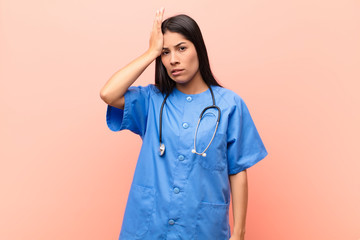 young latin nurse raising palm to forehead thinking oops, after making a stupid mistake or...