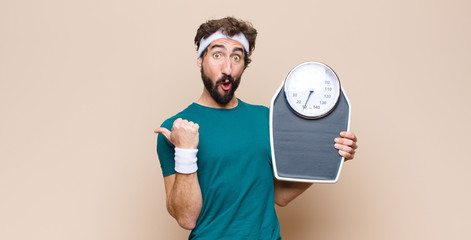young sports man holding a weight skale against flat wall