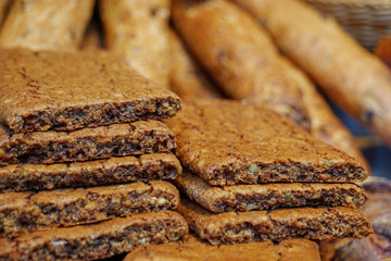 Selected focus at heap and stack of biscuit or cookie with various cereal and whole grain meal and blur background of Baguettes at display of bakery store. 