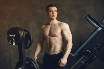 Sports man in the gym. A man performs exercises. Guy in a black shorts.