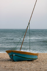 wooden boat on the sand and the blue sea, with the Pontal stone in the background. Macumba Beach Rio de Janeiro Brazil