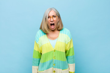 senior or middle age pretty woman looking shocked, angry, annoyed or disappointed, open mouthed and...