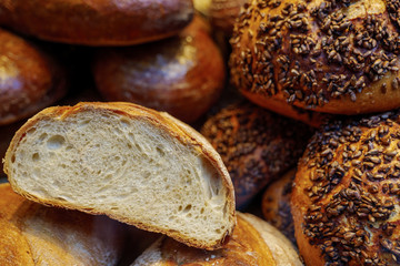 Close up view, cutting heap and stack of wheat breads and rye breads with whole grain meal and rustic mustard crust at display of bakery store. 