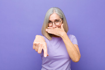 senior or middle age pretty woman laughing at you, pointing to camera and making fun of or mocking...
