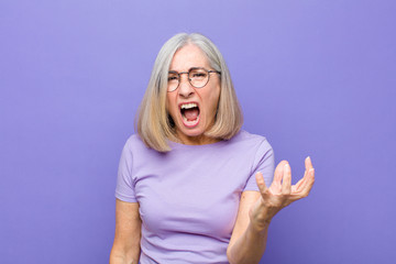 senior or middle age pretty woman looking angry, annoyed and frustrated screaming wtf or what’s...