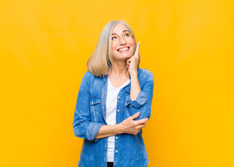 senior or middle age pretty woman smiling happily and daydreaming or doubting, looking to the side