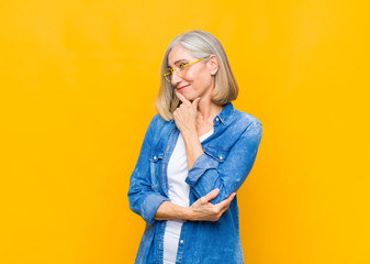senior or middle age pretty woman smiling with a happy, confident expression with hand on chin,...