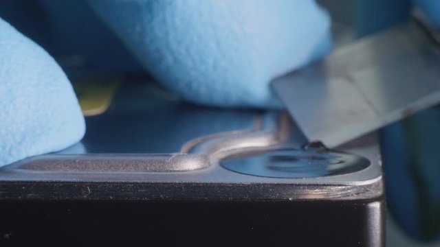 Hands in blue gloves remove sticker seal from hard disk case. Close-up side view