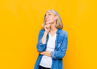 senior or middle age pretty woman feeling thoughtful, wondering or imagining ideas, daydreaming and...