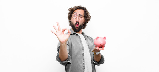 young crazy cool man holding a piggy bank against white wall