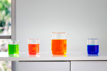 orange,blue and green chemical in beaker place on operating table in laboratory room