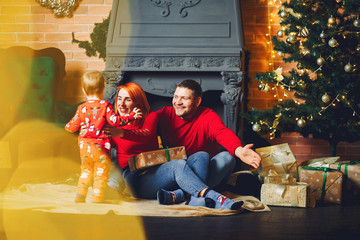 Beautiful mother in a red sweater. Family sitting near christmas gifts. Little boy near christmas tree