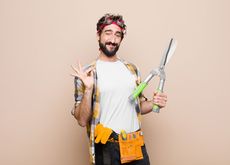 young man housekeeper with a scissors against flat wall