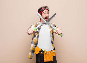 young man housekeeper with a scissors against flat wall