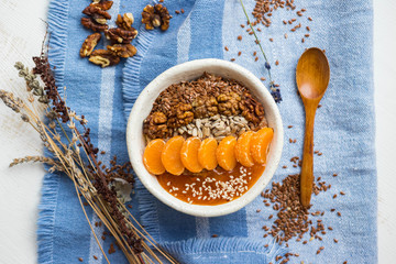 Brown flax seeds healthy dietary breakfast with fruits, sesame, persimmon puree. Losing weight vegan concept.