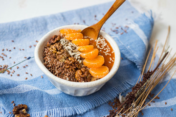 Brown flax seeds healthy dietary breakfast with fruits, sesame, persimmon puree. Losing weight vegan concept.