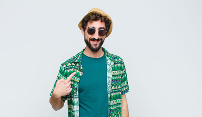 young tourist man looking proud, confident and happy, smiling and pointing to self or making number...