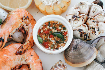 Close up of delicious grilled seafood platter.Tray of mussel, shrimp,prawns and clams with spicy and sour dipping sauce that is packed full of Thai seafood flavor.
