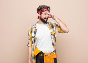 young housekeeper man feeling disgusted, holding nose to avoid smelling a foul and unpleasant...