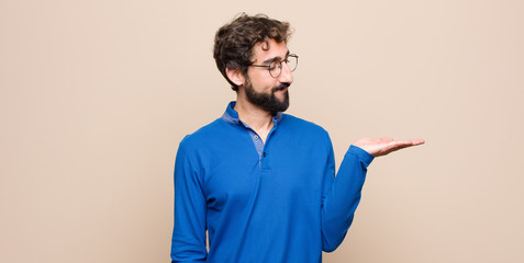 young handsome man feeling happy and smiling casually, looking to an object or concept held on the...