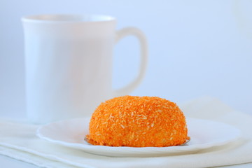 mango and passion fruit mousse on white plate and napkin with cup. Side view, copy space