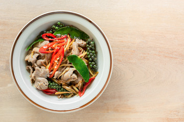 top view of stir fried sizzle duck meat in a ceramic dish on wooden table. asian homemade style food concept.