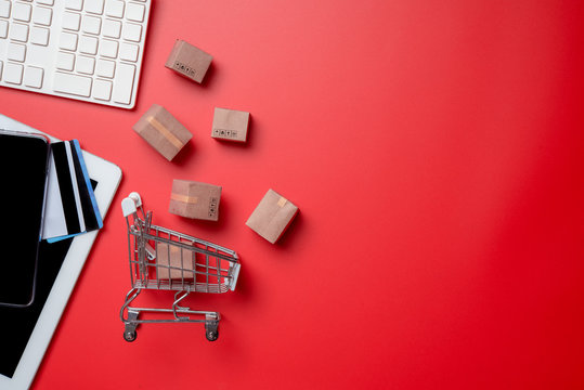 Online shopping,paper boxes,small shopping cart,smartphone, credit card and keyboard against red background