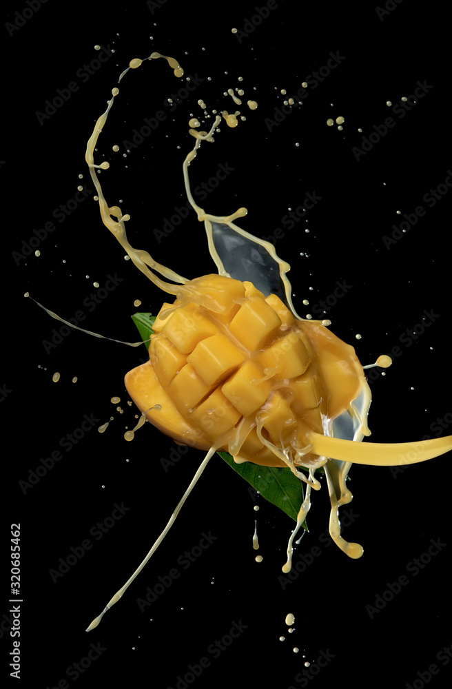 Wall mural mango slice and mango juice splash wave isolated on a black background