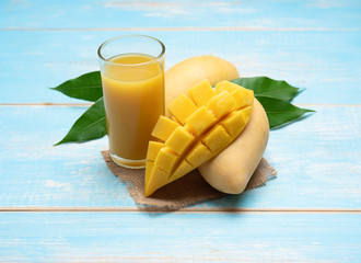 Mango juice in a glass with mango slice on wood