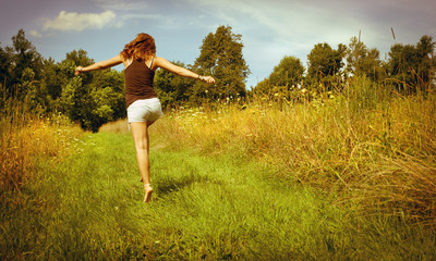 Back of young woman skipping down nature walk way