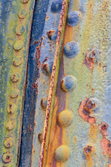 Closeup of a rusty and colorful painted metal with bolts