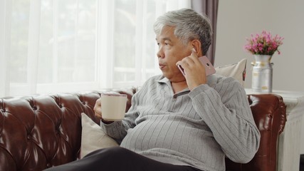 Senior man use wireless earphone listening music and drink coffee
