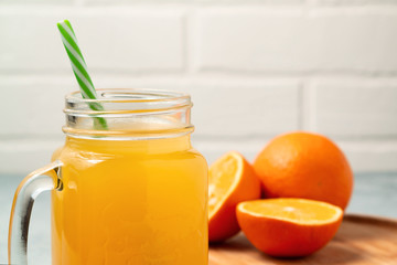 Homemade freshly squeezed orange juice in a mason jar, oranges on wooden dish closeup, copyspace
