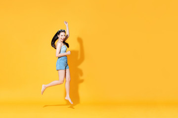 Fototapeta na wymiar Energetic smiling beautiful Asian woman in summer outfit jumping
