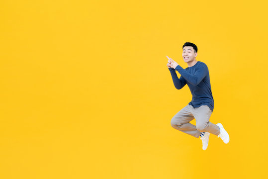 Asian man floating in mid-air pointing two fingers at empty space