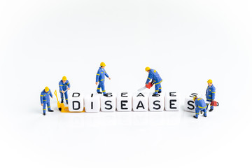 Miniature people men in blue uniform building the cube block with alphabets combine the word Diseases using as Coronavirus flu treatment, illness from virus or medical and healthcare concept