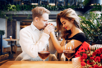 Couple in a restaurant. Lady in a black dress. Woman drinking a vine